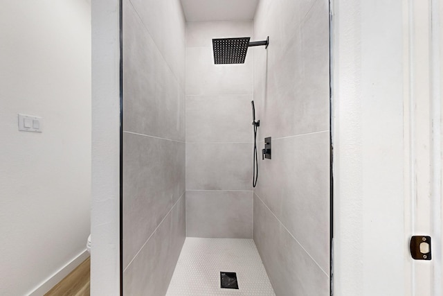 bathroom with a tile shower and toilet