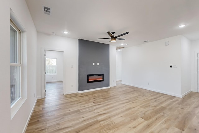 unfurnished living room with ceiling fan, light wood-type flooring, and a fireplace