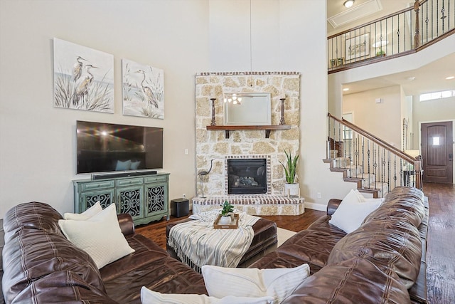 living area featuring baseboards, wood finished floors, stairs, a high ceiling, and a fireplace