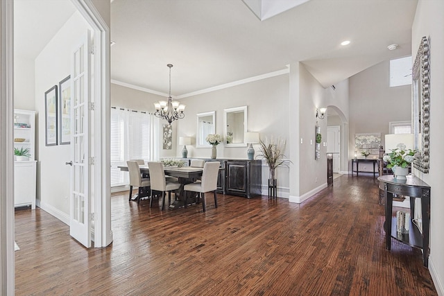 dining space featuring arched walkways, a notable chandelier, baseboards, and wood finished floors