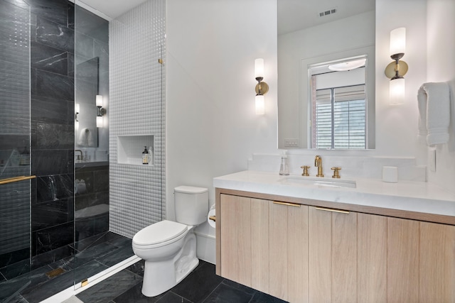 bathroom with vanity, toilet, and tiled shower