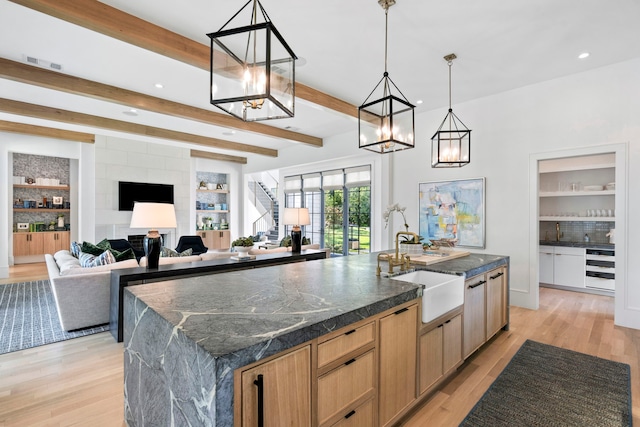 kitchen with sink, wine cooler, hanging light fixtures, beam ceiling, and a spacious island