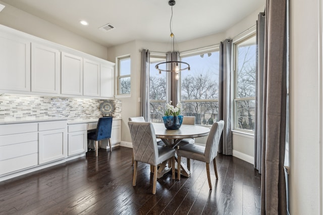 dining space featuring a healthy amount of sunlight, dark hardwood / wood-style flooring, and built in desk