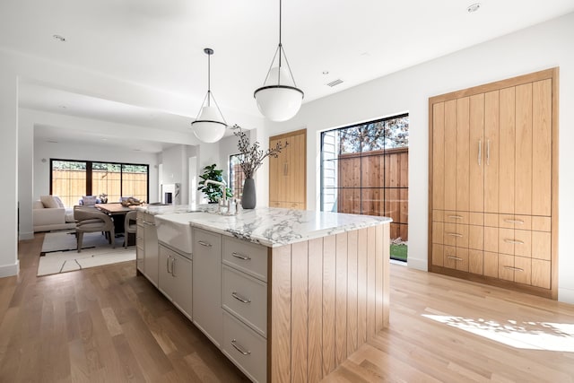 kitchen with visible vents, a sink, a center island, and light wood-style floors