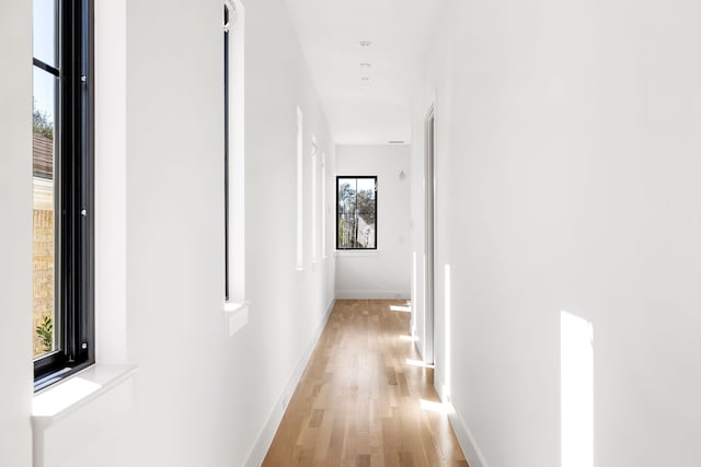 hall featuring light wood-type flooring and baseboards