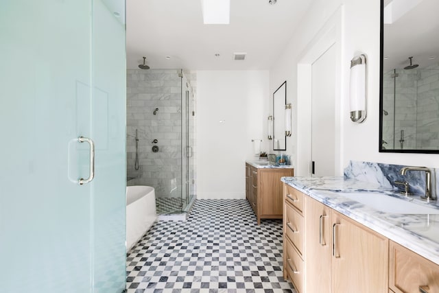 full bath featuring a stall shower, visible vents, tile patterned floors, a sink, and two vanities