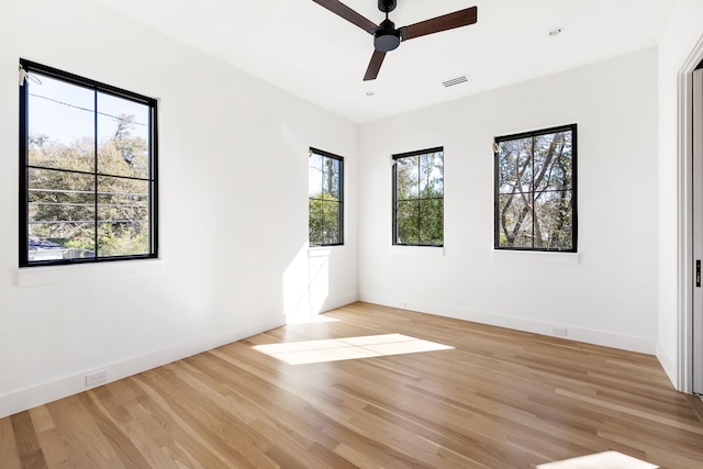 empty room featuring baseboards, a ceiling fan, visible vents, and light wood-style floors