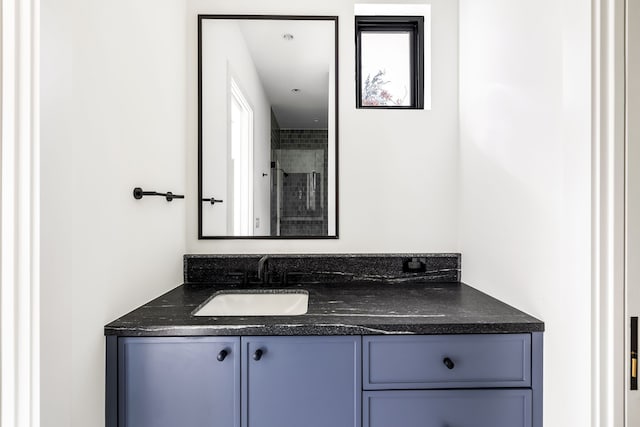 bathroom with tiled shower and vanity