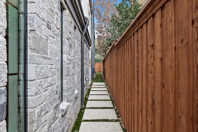 view of home's exterior featuring stone siding and fence