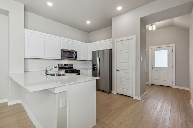 kitchen with sink, white cabinetry, appliances with stainless steel finishes, kitchen peninsula, and backsplash