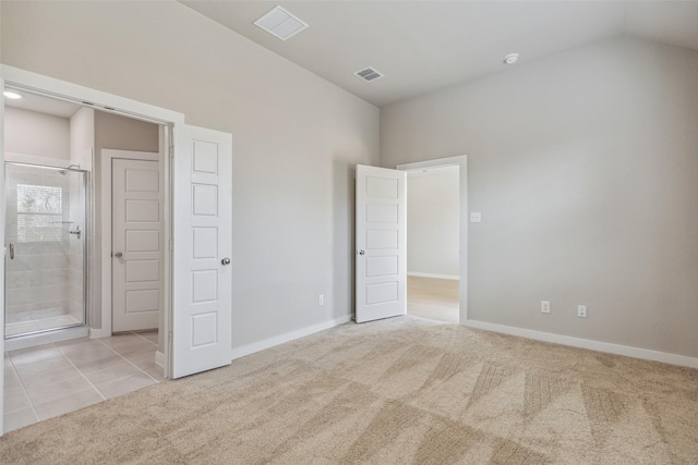 unfurnished bedroom with ensuite bath, vaulted ceiling, and light carpet