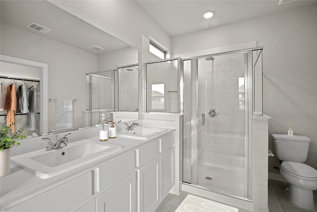 bathroom with vanity, a shower with shower door, tile patterned floors, and toilet