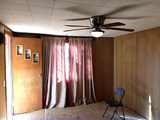 interior space featuring ceiling fan and wood walls