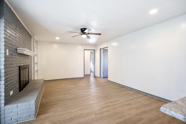 unfurnished living room featuring a brick fireplace, light hardwood / wood-style floors, and ceiling fan