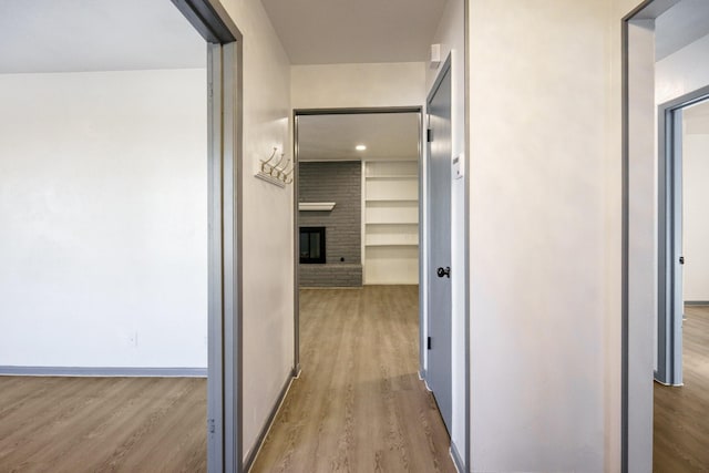 corridor featuring built in features and light wood-type flooring