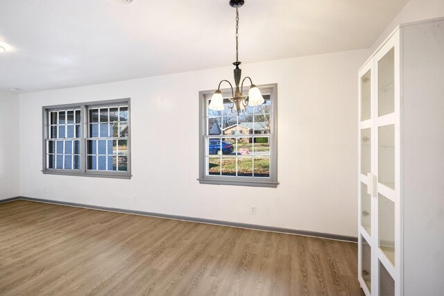 unfurnished dining area with wood-type flooring and a chandelier