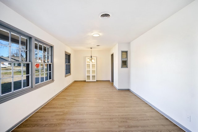 hallway featuring light wood-type flooring and a notable chandelier