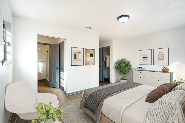 bedroom with a walk in closet, ensuite bath, a closet, and light hardwood / wood-style flooring