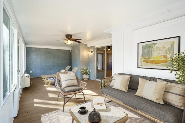 living room featuring brick wall, radiator, hardwood / wood-style floors, and ceiling fan