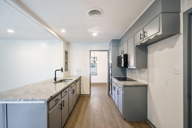 kitchen with sink, gray cabinetry, black appliances, light stone countertops, and light hardwood / wood-style flooring