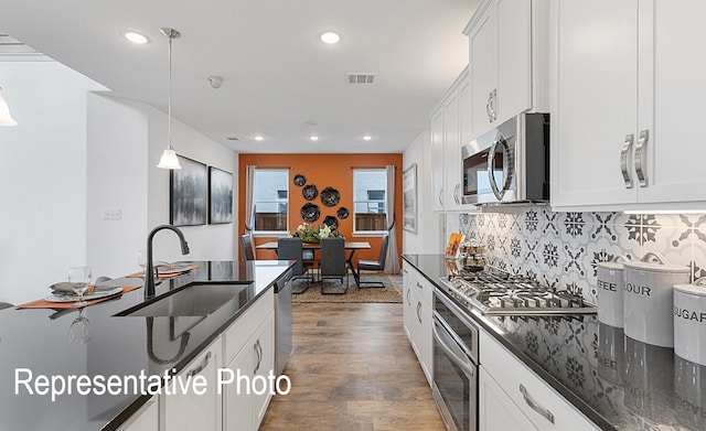 kitchen featuring stainless steel appliances, hanging light fixtures, sink, and white cabinets