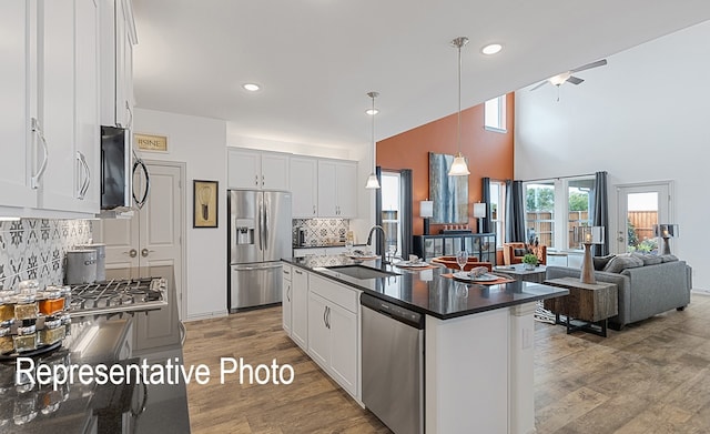 kitchen with pendant lighting, sink, white cabinetry, stainless steel appliances, and a center island with sink