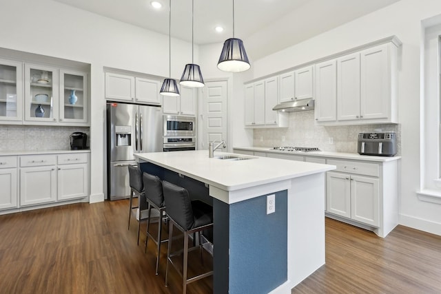 kitchen featuring sink, white cabinetry, hanging light fixtures, stainless steel appliances, and a center island with sink