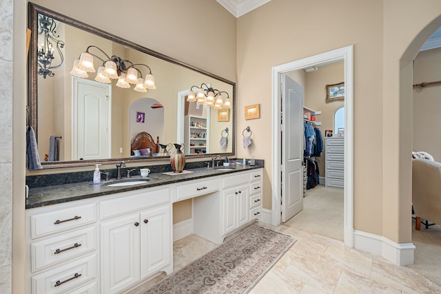 full bath with double vanity, a spacious closet, a sink, and baseboards