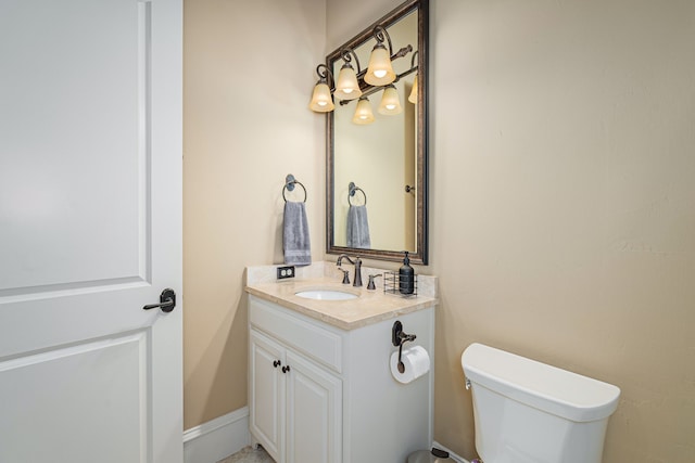 bathroom with baseboards, vanity, and toilet