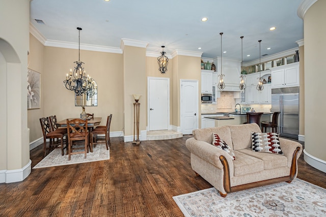 living room featuring a chandelier, dark wood-type flooring, visible vents, baseboards, and crown molding