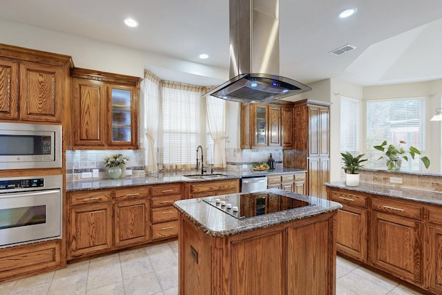 kitchen featuring sink, island range hood, a center island, stone counters, and stainless steel appliances