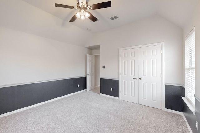 unfurnished bedroom with lofted ceiling, light colored carpet, a closet, and ceiling fan