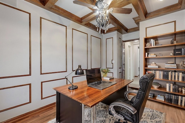 office space featuring light wood-type flooring, ornamental molding, coffered ceiling, ceiling fan, and beam ceiling