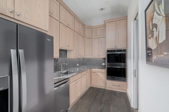 kitchen featuring sink, black fridge, vaulted ceiling, light brown cabinets, and dishwasher