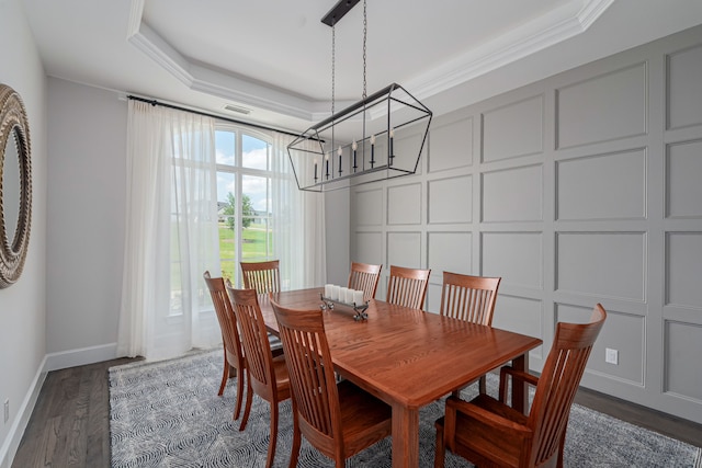 dining space featuring dark hardwood / wood-style flooring, a tray ceiling, ornamental molding, and an inviting chandelier