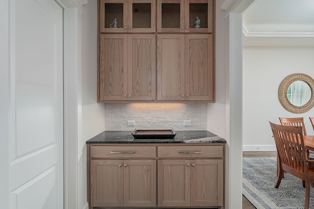 kitchen featuring tasteful backsplash, crown molding, and dark stone counters