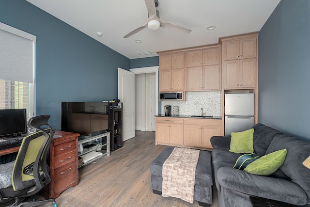 living room featuring sink, light hardwood / wood-style floors, and ceiling fan