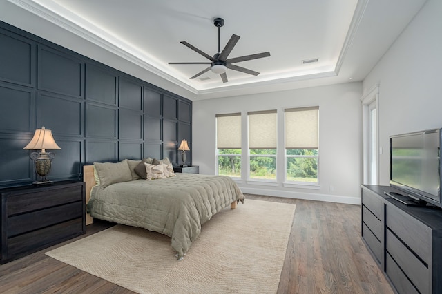 bedroom featuring ceiling fan, dark hardwood / wood-style flooring, and a raised ceiling