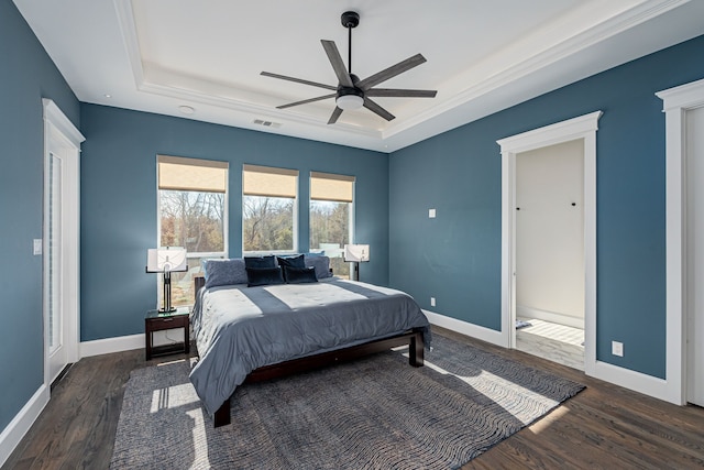 bedroom with dark hardwood / wood-style flooring, a tray ceiling, and ceiling fan