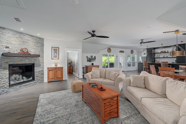 living room with hardwood / wood-style floors, a stone fireplace, and ceiling fan