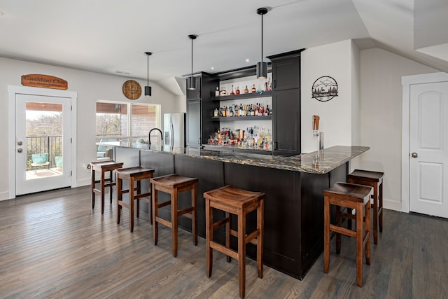 bar with pendant lighting, stainless steel fridge, dark stone counters, and vaulted ceiling