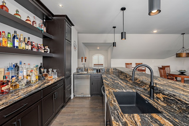 kitchen with dark hardwood / wood-style floors, pendant lighting, sink, dark stone counters, and dark brown cabinetry