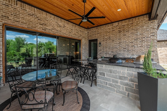 view of patio featuring a bar, grilling area, ceiling fan, and exterior kitchen