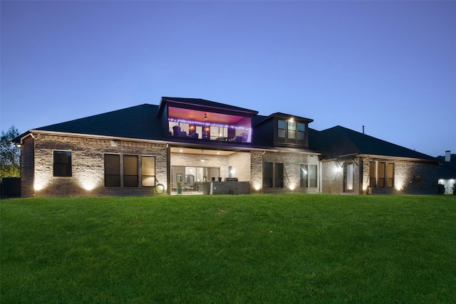 back house at dusk with a lawn