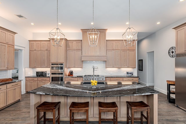 kitchen with a kitchen island, a breakfast bar, light brown cabinets, and dark stone counters