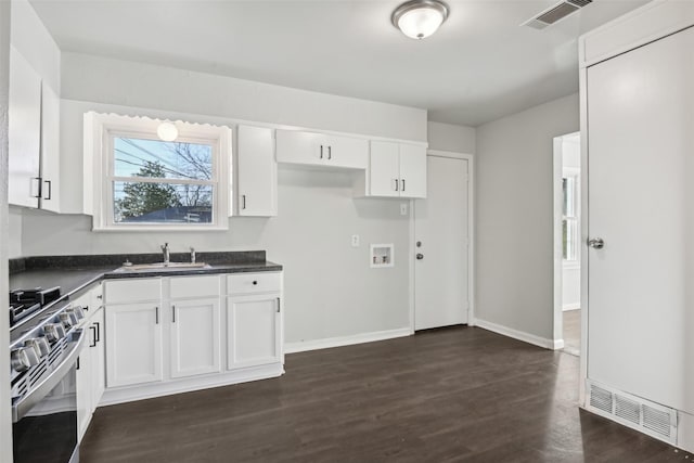 kitchen with white cabinetry, sink, stainless steel range, and dark hardwood / wood-style flooring