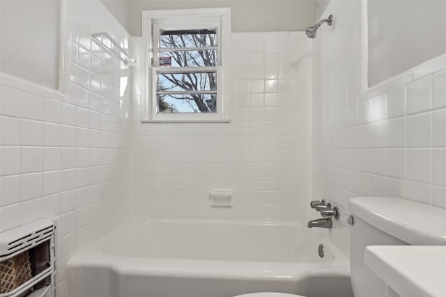 bathroom with tile walls, tiled shower / bath combo, heating unit, and toilet