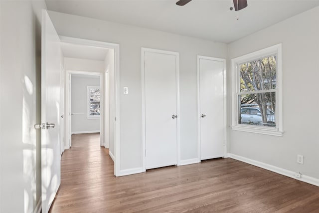 unfurnished bedroom featuring hardwood / wood-style flooring, ceiling fan, and multiple windows