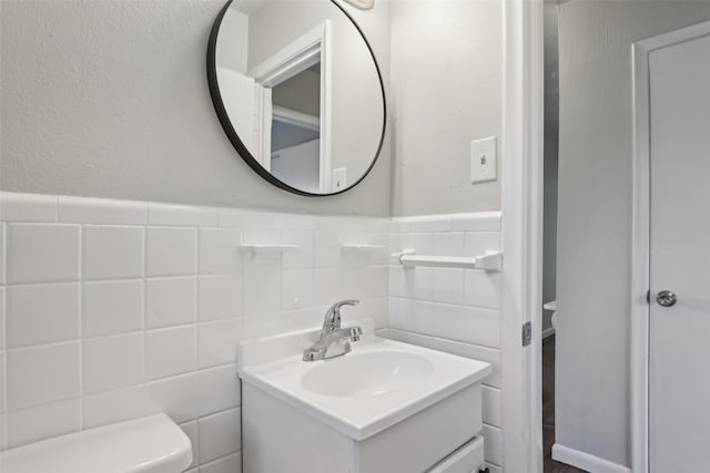 bathroom featuring vanity, toilet, and tile walls