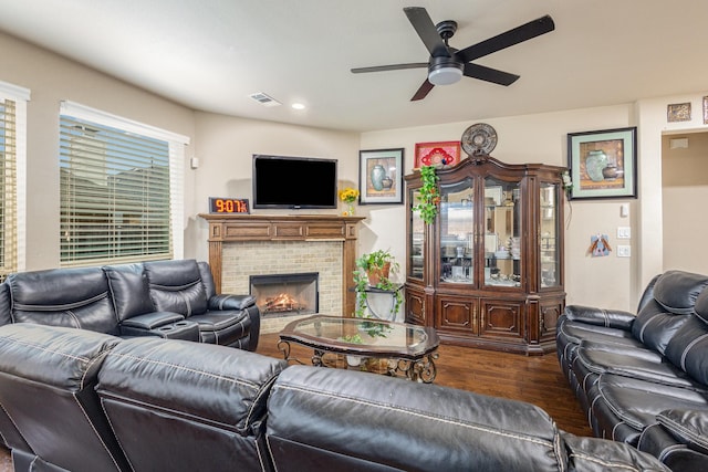 living room with a brick fireplace, dark hardwood / wood-style floors, and ceiling fan